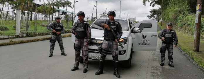Guardias de seguridad uniformados y en posición de defensa con sus armas por delante de una camioneta.