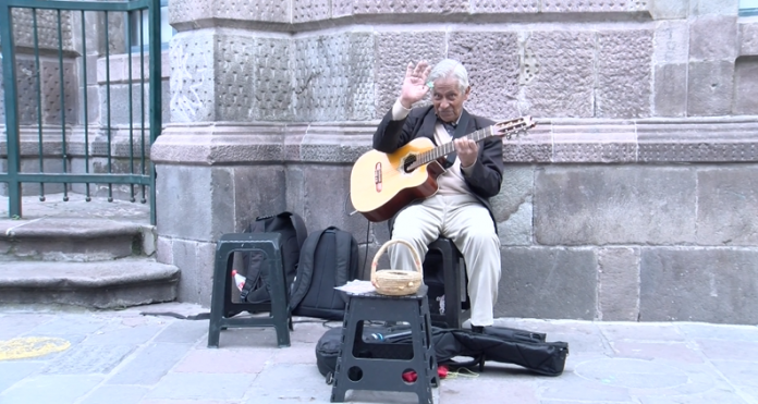 Patricio López, sentado y con su requinto en mano saluda a las cámaras