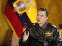 Daniel Noboa, presidente de Ecuador, sentado en una entrevista con la bandera del país en su espalda.